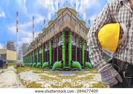 Worker holding hard hat working at cooling tower of Industrial power plant