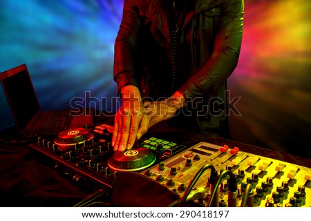 Disc jockey mixes turntable with dance song in nightclub at party