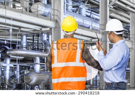 Engineer and foreman working with equipments and machinery in a industrial factory
