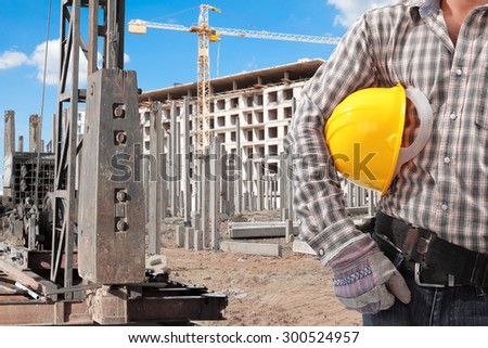 Worker working at pile driver works to set precast concrete piles in a construction high building area