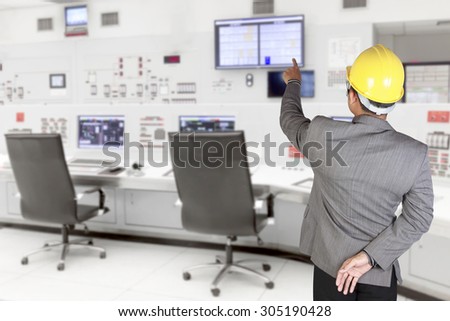 Engineer pointing at monitor screen for command working at control room of a modern thermal power plant