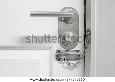 the white door is closed on a silvery security chain