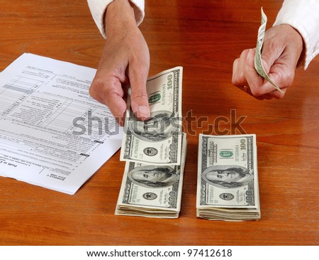 Close up of hand counting cash, near a  tax form