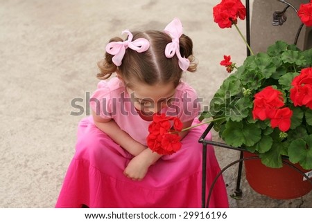 Toddler girl in pink dress smelling a flower