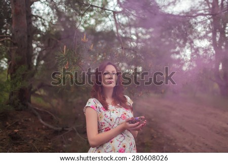 Beautiful pregnance woman near the green trees. Purple  fog, mist. Beauty Model Girl. Perfect Creative Hair Style. Hairstyle.  Mother
