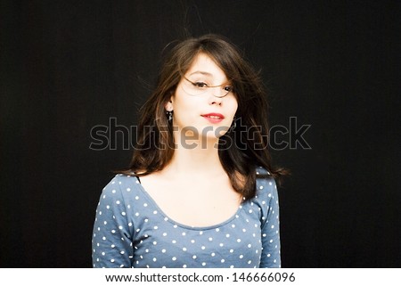 Portrait of a young  woman with polka dot dress and her hair in the wind over black background