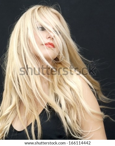 Wonderful blonde woman with hair in the wind on black background