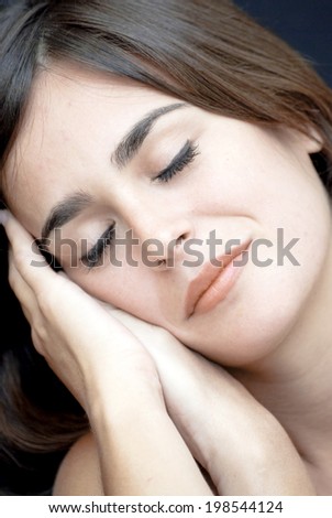 Portrait of Beautiful Young Woman asleep resting his face on his hands Over Black Background