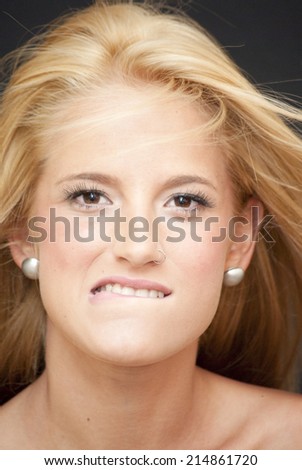 Portrait of Beautiful Blonde Woman biting his lip Over Black Background