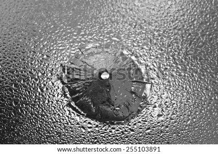Bullet aperture in the wet glass, the broken glass. Black white conceptual photo - danger