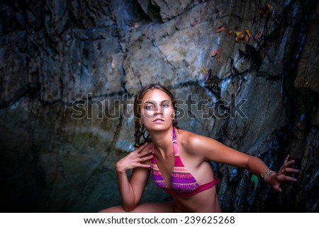 Beautiful sexy model posing in water of waterfalls wearing bikini swimwear at summer time