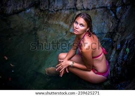 Beautiful sexy model posing in water of waterfalls wearing bikini swimwear at summer time