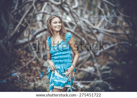 Portrait of a beautiful young smiles woman in turquoise dress standing by trees In jungle forest