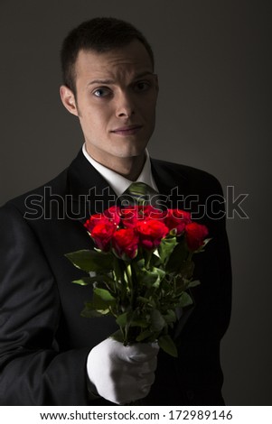 attractive young man with bouquet of roses in front of grey background