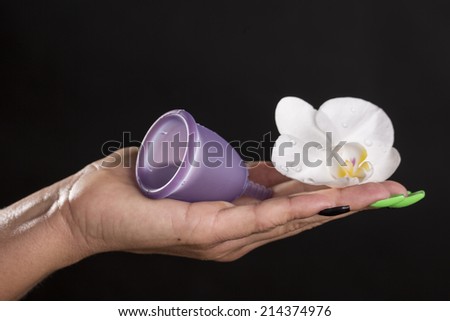 Woman hand holding intimate funnel ( for periods) and white flower (