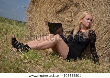 Sexy woman on laptop in hay stack on a summer day