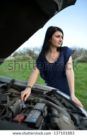young brunette girl with a broken car with open hood