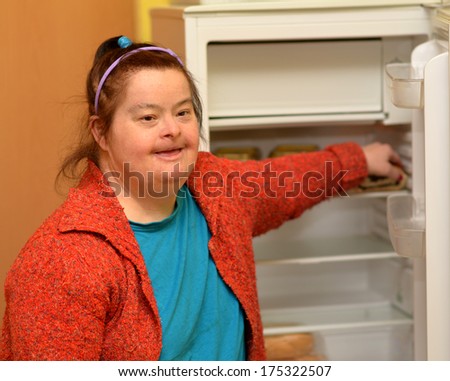 a hungry woman with down syndrome opening fridge