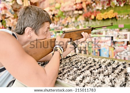 young man holding gun and shooting, playing shooting games while visiting an amusement park