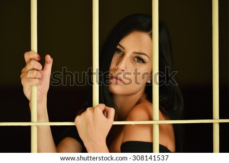 Young woman looking from behind bars. trapped woman behind iron bars