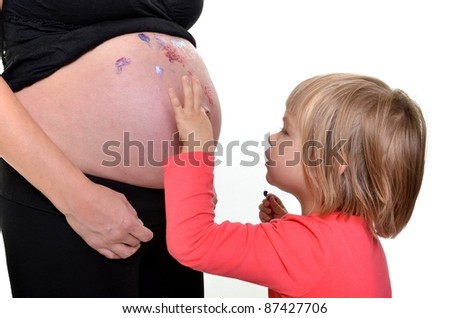 little girl painting on her mothers pregnant belly