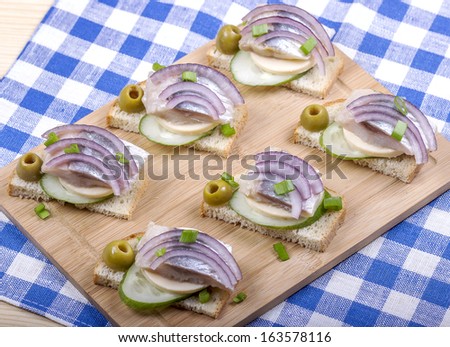 Sandwiches of white bread with fresh cucumber, cheese, herring, onions and herbs