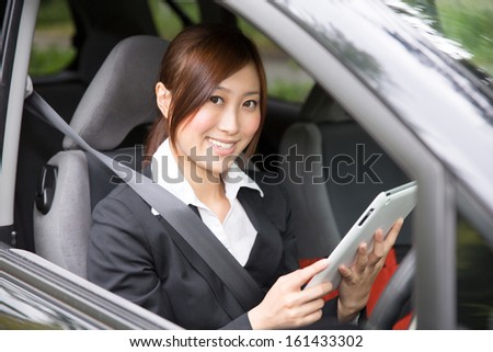 Beautiful young asian woman using tablet computer in a car