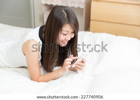 young attractive asian woman  to see a smart phone in bed