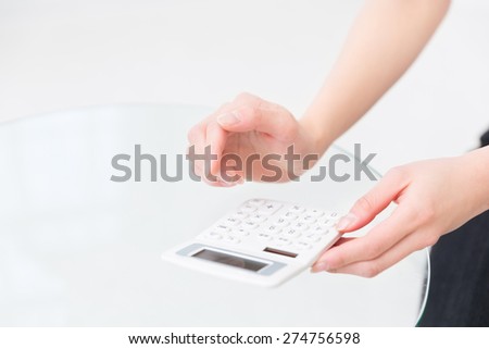 Hand of a woman that uses an electronic calculator