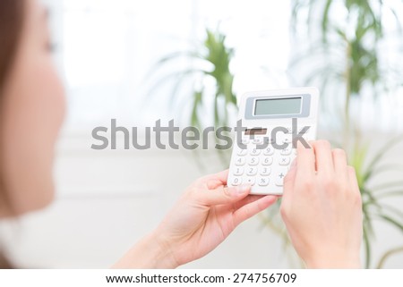 Hand of a woman that uses an electronic calculator
