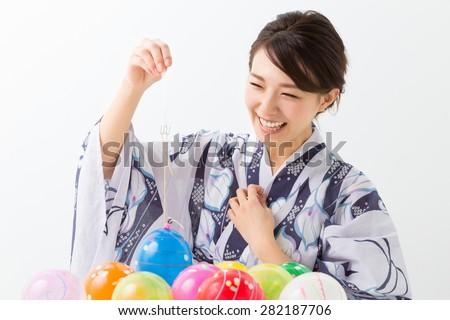 young attractive Japanese woman in a Yukata who does yo-yo fishing