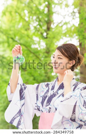 young attractive Japanese woman in a Yukata having a wind bell