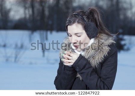 Woman hands warm breath in winter park