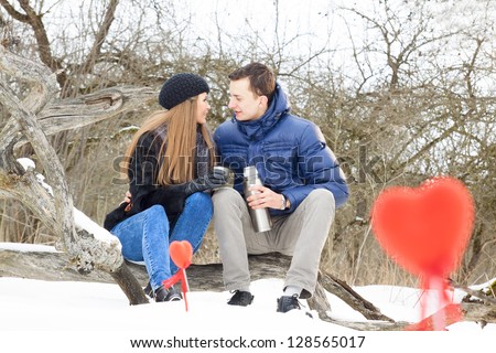Beautiful adult couple in forest sitting an drinking tea
