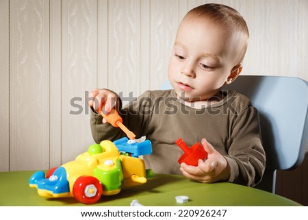 little boy repairs auto sitting on the table