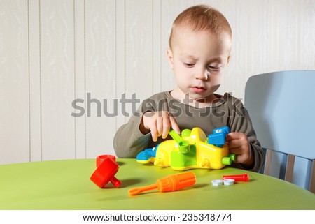 Little boy repairs auto sitting on the table