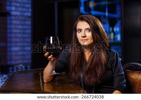 pretty woman in nightclub sitting alone have a glass of wine