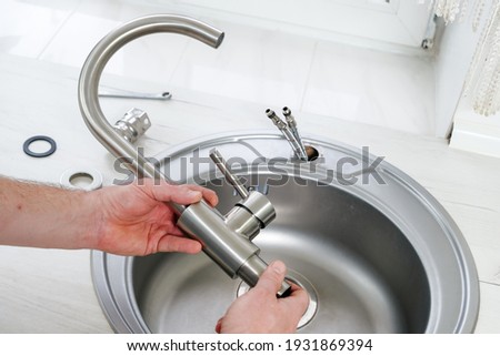 Close-up plumber hands holds a new faucet for installing into the kitchen sink, plumbing work or renovation Photo stock © 