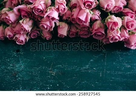 Pink roses in bloom on a blue wooden table