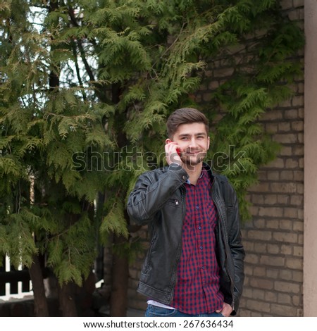 Handsome hipster in leather jacket speaking on the phone outdoor