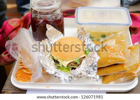 Delicious hamburger with a bottle of jam and three bags of curry and several pancakes./lunch/sandwich