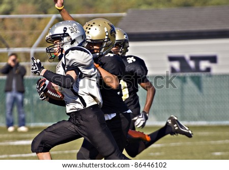 CUMMING, GA - OCTOBER 8: Several unidentified age 11 to 13-year-old  boys run with the ball and block during a football game, the Raiders vs the Saints, on October 8, 2011 in Cumming, GA.