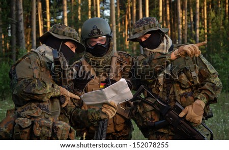 Three german soldiers discuss a plan of action. Coordinate the team.