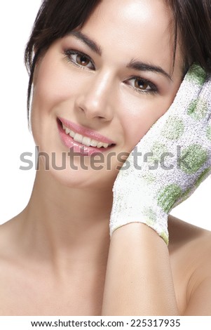 Beautiful young woman applying scrub glove on her perfect skin on white
