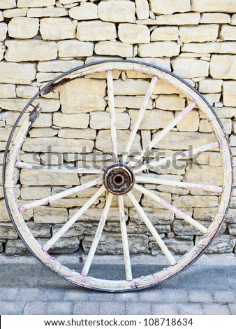 Old Vintage broken wood wheel in Provence on a traditional stone wall background. France.
