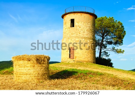 Tuscany, Maremma typical countryside sunset landscape with hill, tree, straw bales and rural tower.