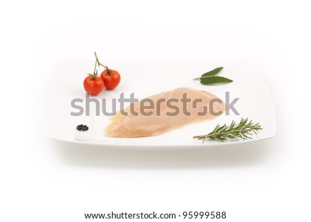 Raw chicken breast on white minimal dish with herbs, spices and small tomatoes