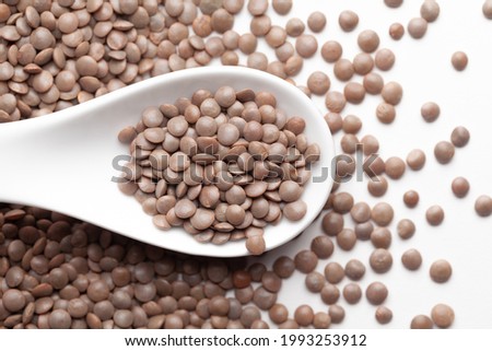 Macro Close up of Organic masoor dal (Lens culinaris) or whole brown dal on a white ceramic soup spoon. Top view,  over gradient background of itself. Foto d'archivio © 