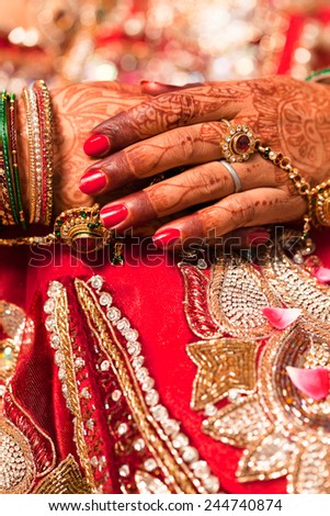 Hand detail of indian bride with decorative bangle and gold ring.