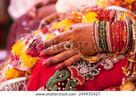 Hand detail of indian bride with decorative bangle and gold ring.